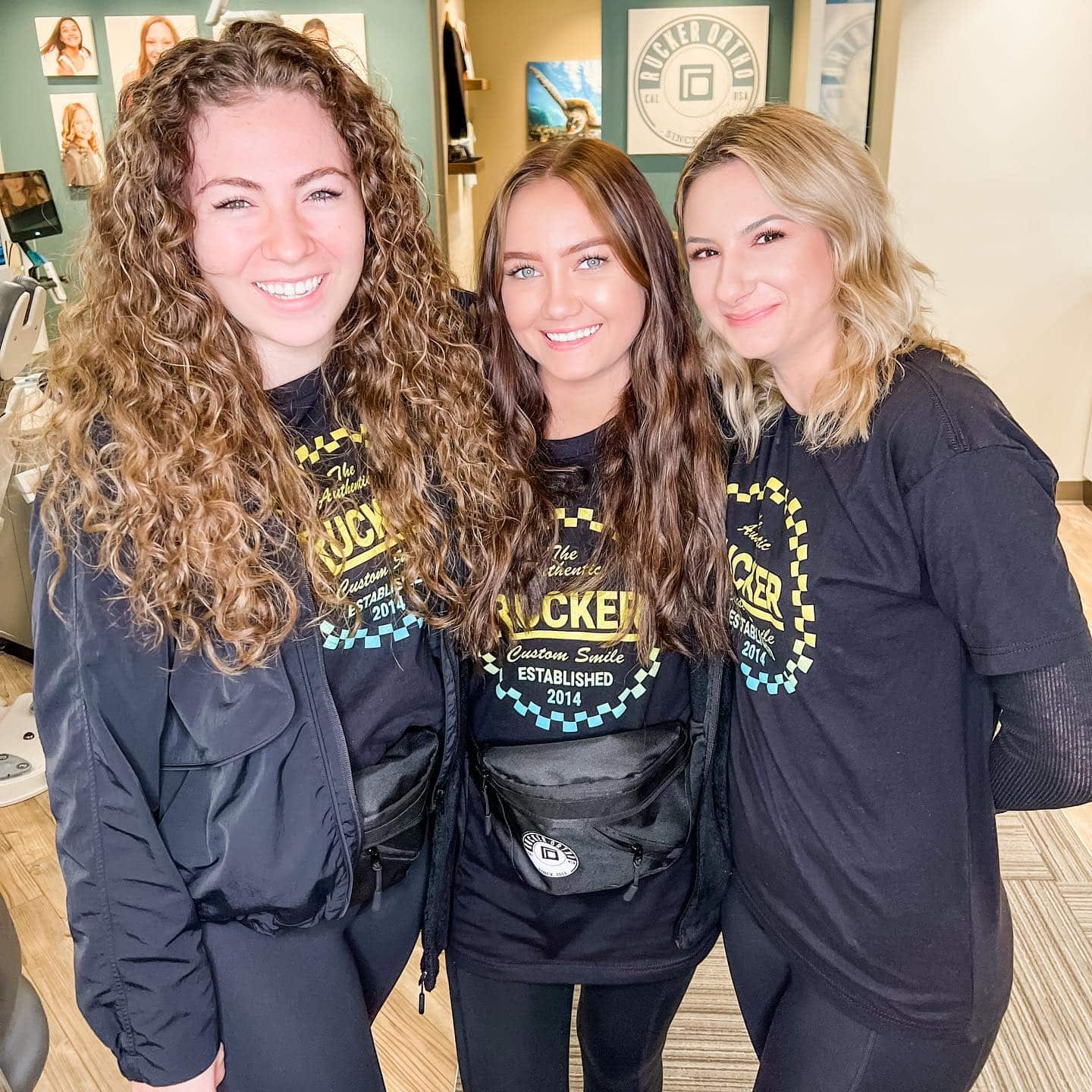 Three smiling young women at the Rucker Orthodontics office in Temecula, CA. wearing Rucker Orthodontics t-shirts.